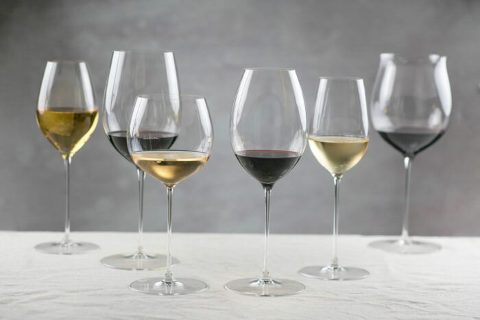 Seks vinglass med ulike høyde og form, plassert i en uryddig rekke.